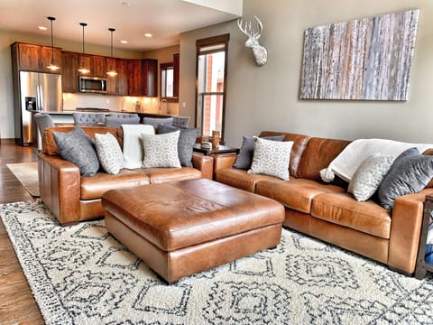 Great room with large and deep seated leather love seat and couch.