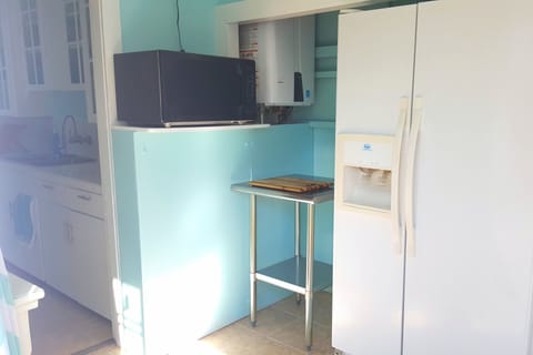 Kitchen has large fridge, microwave, toaster oven, coffee maker, pots, dishes.