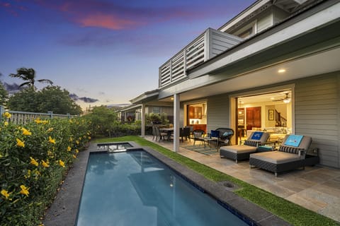The back exterior of this Kona Hawai'i vacation rental, complete with a pool and bright landscaping.