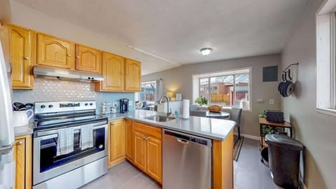 Bright and inviting kitchen with wooden cabinetry, stainless steel appliances, and a modern backsplash, seamlessly flowing into the dining area.
