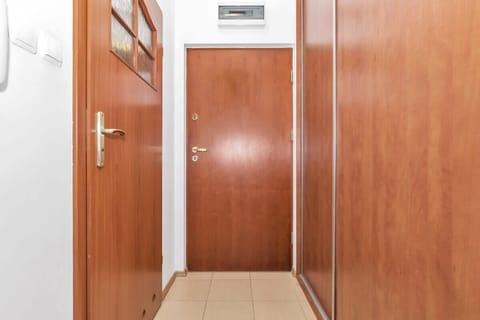 A hallway with wooden doors and built-in closets provides a practical entry space. The sleek design and neutral tones make it a functional yet attractive area.