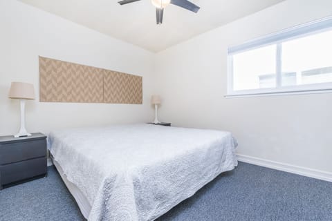 Fourth bedroom outfitted with King bed, linens, ceiling fan and closet. Located along central hallway.