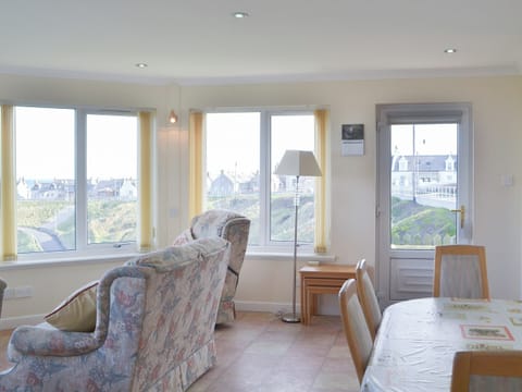 Sun room with dining area and dramatic views over the town | White Gables - Scott Holiday Cottages, Portknockie
