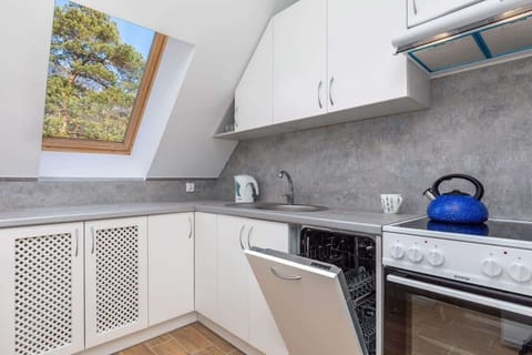 A modern kitchen with white cabinets, a gray countertop, a built-in oven, and a skylight window that illuminates the space.