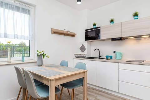 A view of the dining area with a wooden table and light-colored chairs. The space is bright, thanks to large windows and a light color scheme.