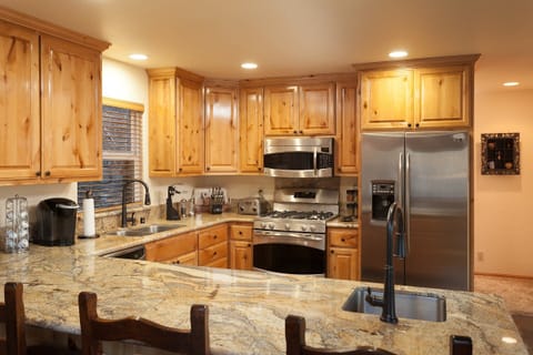 Kitchen with stainless steel appliances and a breakfast bar with another sink and 4 stool for extra seating.
