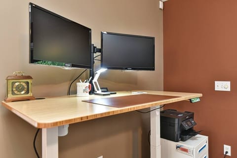 Computer workspace area in living room complete with two monitors and a printer you can use