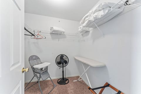 Master bedroom walk in closet. Fan, iron board and high chair
