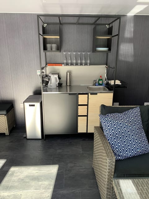 Small kitchen with fridge, kettle, coffee machine, crockery, glasses and cutlery