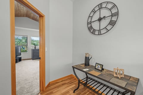 Charming hallway entry featuring a rustic decorative clock and accent table with bench seating. Offers a warm welcome and practical space for everyday use.