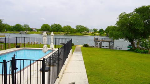 View of pool, yard, dock, and lake from back porch. 