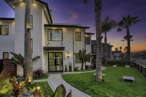 front of house with a cornhole arena (two sets) and a firepit seating area