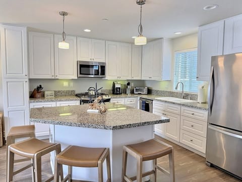 This breezy beach-style kitchen is made for gathering and grazing, featuring a spacious island, sleek stainless steel chef-grade appliances, and plenty of countertop space for prepping the day’s catch or mixing up sunset cocktails.