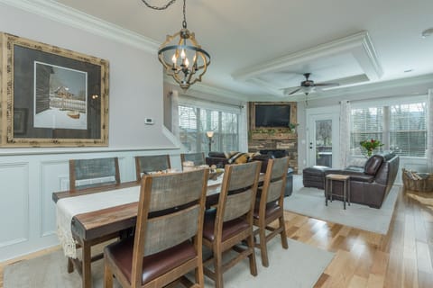 Open-concept living and dining room with hardwood floors, stone fireplace, and natural light.