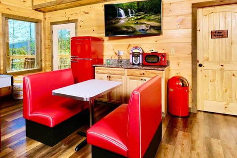 Retro red amenities in the game room include a diner booth set, fridge, microwave and mini juke box.