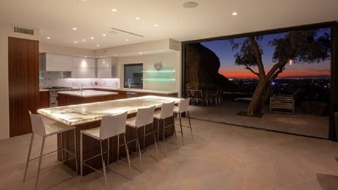 Stylish kitchen with a glowing island, city views, and twilight ambiance.