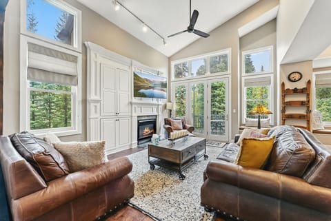Living room (main floor): Gas fireplace, flat-screen TV, built-ins, armchair, coffee table, deck access with gas grill