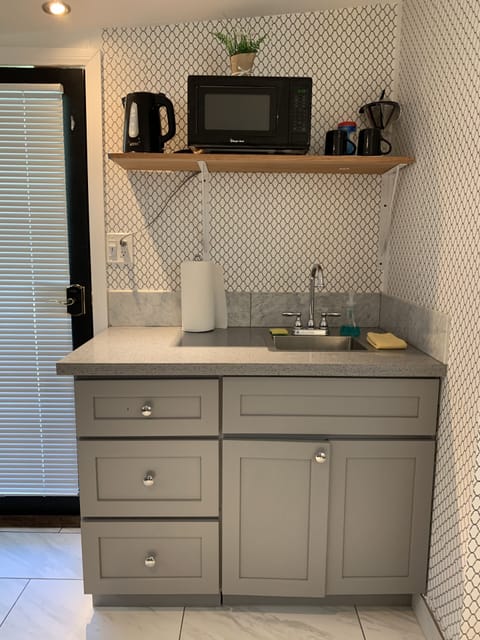 Kitchenette: sink, micro, water pot and dishes with silverware.