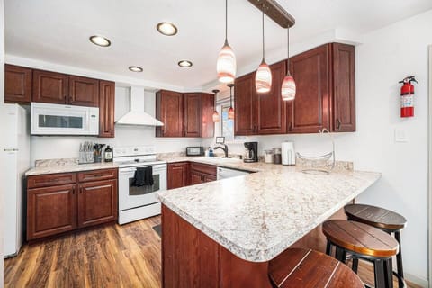 - Cook up your favorites in this fully equipped kitchen with modern appliances
- Rich wooden cabinetry and pendant lights add warmth and charm to the space
- Spacious countertops and breakfast bar seating make meals easy and social