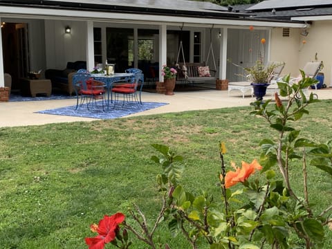 Huge fenced back yard with flowers, ferns and big trees. Lot of out sitting area