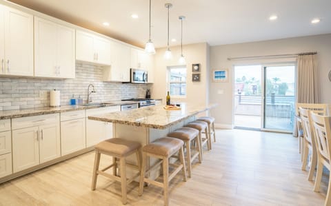 UNIT A (4Bdrm): The kitchen showcases professional-grade appliances, seamlessly connecting to the living room and offering ample space for food preparation.
Dining table for 6 guests, plus bar stools at the nearby kitchen island.