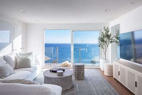 Enjoy sweeping views of the Pacific Ocean from the beachy modern living room, designed and furnished by Restoration Hardware.(
