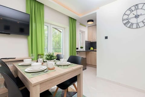 A modern kitchen with light wooden cabinetry, a black countertop, and a minimalist design.