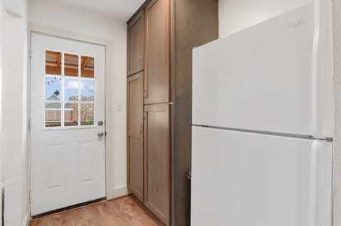 Convenience at your fingertips! This area features a large refrigerator, pantry storage, and easy access to the outdoors.