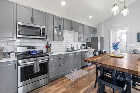 Stocked kitchen with gas stove, microwave, drip coffee maker, & cooking supplies