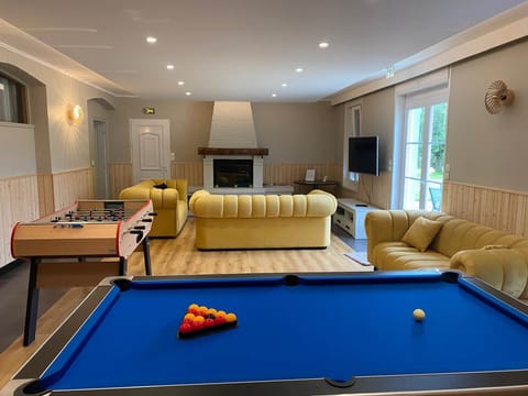 Espace détente lumineux avec cheminée, jeux et TV : tout le confort d’un gîte rural de charme en Hauts-de-France