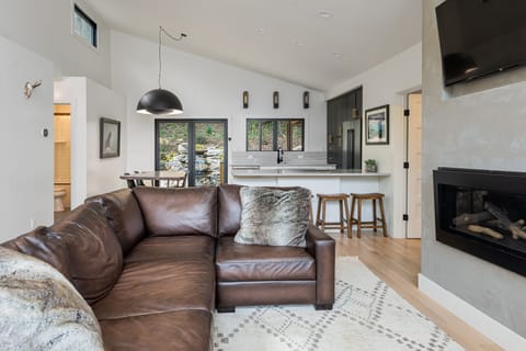Luxe living room w/floor-to-ceiling woodland views & gas logs fireplace.