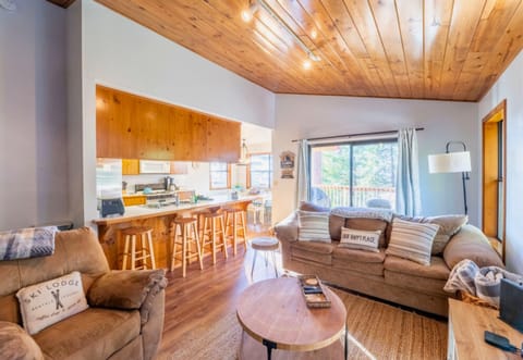 A warm and inviting cabin interior blends open-plan living with rustic coziness and a touch of modern comfort.
