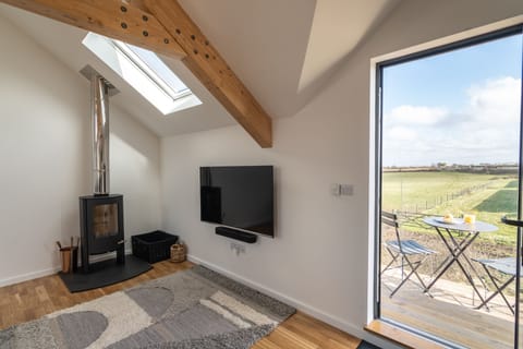 Cedar House, St Agnes. First floor: Sitting area with comfortable seating area, Smart television, a wood burning stove, and balcony with countryside and distant sea views