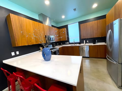 Fully Equipped Kitchen With Spacious Countertops And An Island With High Chairs For Dining