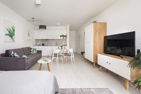 A cozy sleeping nook integrated into the studio space, with a double bed and soft, neutral bedding.