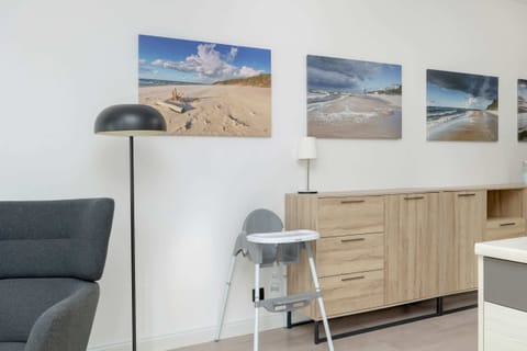 A cozy living room with light wooden flooring and a gray sectional sofa, complemented by stylish, modern decor and soft lighting.