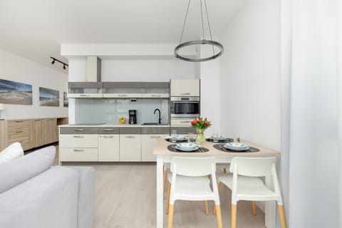 A spacious, modern kitchen and dining area featuring sleek white cabinets and appliances, with light gray tones for a clean, sophisticated look.
