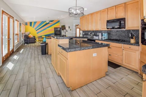 "Spacious and modern kitchen with warm wood cabinetry, sleek black granite countertops, and a stylish island—perfect for cooking and entertaining!"