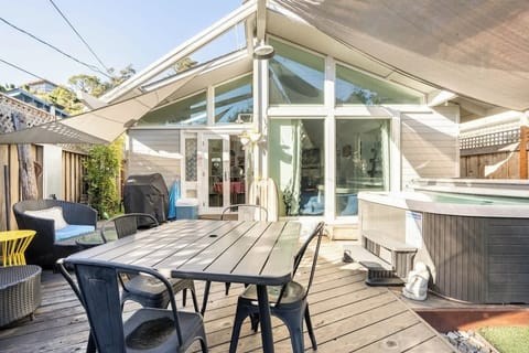Bright patio with dining, lounge seating, and hot tub access — ideal for romantic evenings, family BBQs, or business travelers enjoying a coastal retreat.