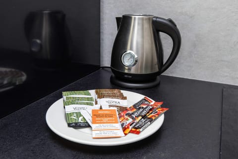 Coffee and tea-making station on a black countertop with a coffee machine and toaster.