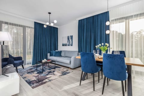Living and dining area with a blue sofa, a small dining table, and blue curtains, creating a cozy and unified look.
