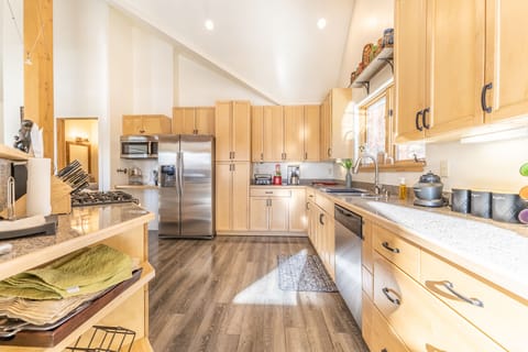 High end full-size kitchen with granite countertops, modern stainless steel appliances and vaulted ceiling.