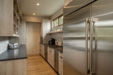 Large chef's pantry behind kitchen with full size fridge and freezer, dishwasher, and sink