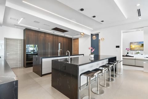 Modern chef’s kitchen featuring granite island, designer lighting, and breakfast bar