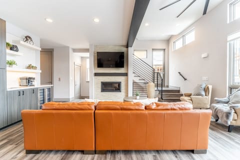 Spacious open concept living area with mounted smart TV, gas fireplace, hardwood radiant heat flooring, ample seating and access to the private balcony.