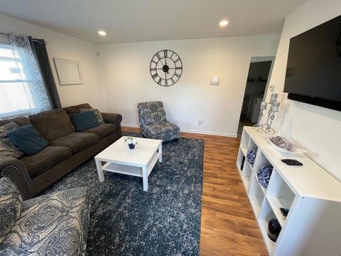 Front door opens up to living room that includes a smart tv, two chairs, couch