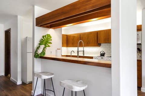 Chic kitchen with koa wood cabinetry, updated appliances, and a breakfast bar for two.