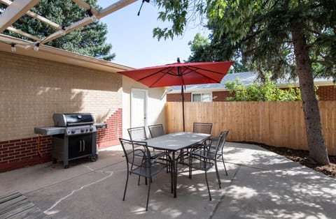 Backyard patio includes a propane grill and outdoor seating with large umbrella