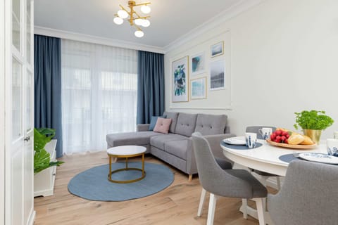 Dining area with a round table, soft gray chairs, and elegant decor in a bright space.
