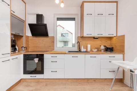 A compact kitchen with wooden cabinetry, a stovetop, microwave, and coffee machine neatly arranged.
